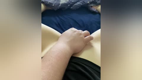 Video of a close-up, blurred image of a hand pressing into a person's stomach, likely male, with a blue shirt and dark pants visible in the background.