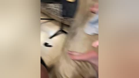 Video of a person with blonde hair, partially obscured by a black hat, with a hand touching their hair, in a dimly lit room.