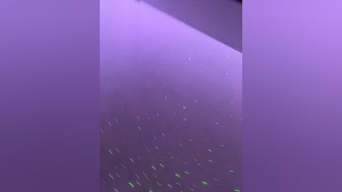 Video of a minimalist, abstract art piece featuring a soft, lavender gradient background with scattered, greenish-yellow specks, creating a dynamic and ethereal atmosphere.