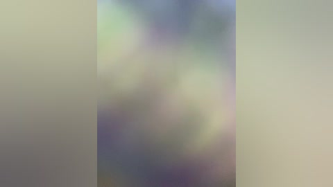 The image is a blurred video with soft, pastel colors of green, blue, and purple, creating a dreamy, abstract effect. The background and foreground are indistinguishable, lacking any distinct objects or details.