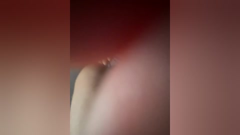 A blurred, close-up video of a human buttock, showing smooth skin and a subtle reddish hue, with a soft, diffuse background.