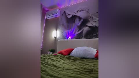 Video of a dimly lit bedroom with a beige headboard, green sheets, and a black-and-white wall mural. Pink LED lights create a romantic ambiance.