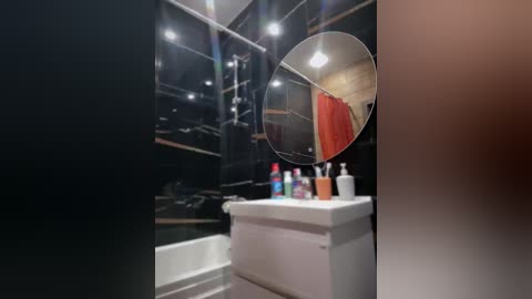 Video of a compact, modern bathroom with black walls, white sink, mirror, and orange shower curtain visible through a round mirror.