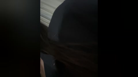 A dimly lit video captures an intimate moment between two people, with the focus on a hand gently holding a person's face. The background is blurred, emphasizing the closeness and the moment.