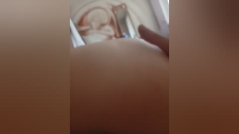 A blurred video of a nude woman lying in bed, with a hand gently caressing her breast, seen from a low angle.