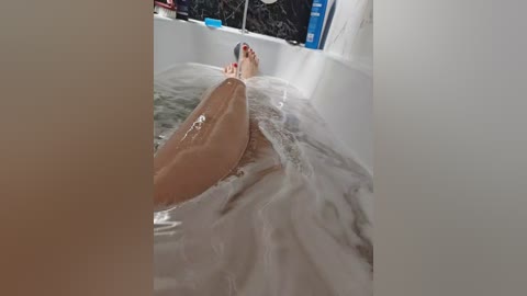 A video of a white person with light skin, reclining in a bathtub with frothy water, head tilted back, looking relaxed. The background features a dark, blurred setting.