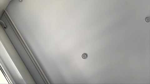 Video of a modern, minimalist ceiling with a smooth, white finish. Three circular recessed lights are evenly spaced across the surface, adding a subtle, contemporary touch.