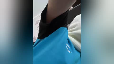 Video of a person wearing a blue and black sports jacket with a white shirt underneath. The image is slightly blurred, with a soft focus.