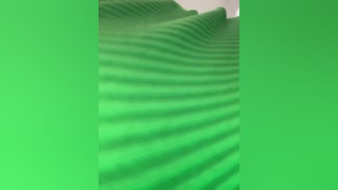 Video of wavy, green fabric, possibly plastic, with rippled, undulating patterns. The fabric has a smooth texture and is uniformly colored, creating a serene, almost aquatic ambiance. The image is cropped to focus solely on the fabric's surface.
