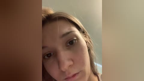 Video of a young Caucasian woman with light skin and brown hair, slightly cropped. She gazes directly into the camera, framed by two vertical wooden posts, creating a partition effect.