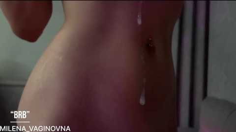 Video of a naked person, possibly female, with a visible wet, dripping genital area, in a bathroom setting. Text \"MILA EVA VAGINOVNA\" in white, lower-left.