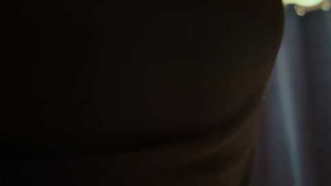 A dimly lit, close-up video of a person's face, with dark, indistinct features and blurred background, suggesting a low-light or night-time setting.