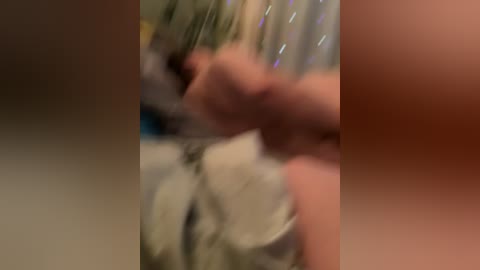 A blurry video shows a person wearing a white shirt with a blurred, possibly moving hand holding a knife. The background is indistinct. The image appears to be taken indoors with muted lighting.