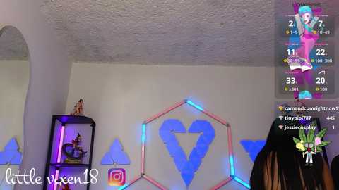 Video of a bedroom with white walls and a ceiling fan. Hexagonal heart lights and a black shelf with a figurine are visible. Overlay shows a live stream with a person and an avatar.