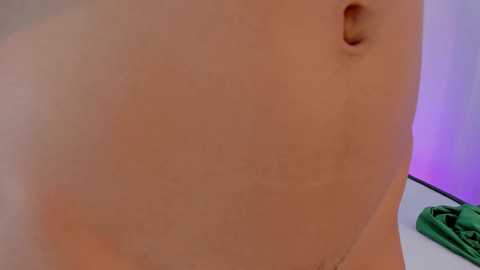 Video of a close-up of a pale, smooth, unclothed upper torso with a small, natural navel, and faint pinkish-purple light in the background.