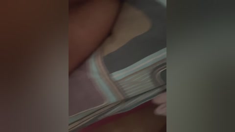 A close-up video of a person's hand holding a metallic object, possibly a pen or tool, with a blurred background. The hand is slightly out of focus, highlighting the object's reflection and texture.