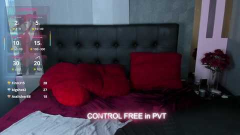 Video of a dark, plush bed with red pillows and bedding, surrounded by a sleek, modern room with soft lighting.