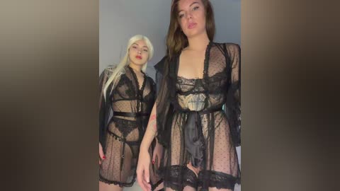 Video of two women in black, sheer, polka-dot lingerie; one with platinum blonde hair, the other with brunette. Both have fair skin, and the background is a blurred gradient.