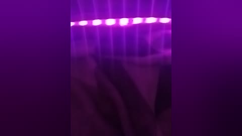 A video of a blurred, purple-lit room with faint outlines of people dancing in the background. The lighting creates a hazy, dreamy atmosphere with soft, diffused shadows.