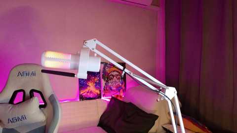 Video of a gaming setup with an A4Tech gaming chair, a desk lamp, and two posters featuring colorful anime characters. The room has a purple ambient light and beige walls.