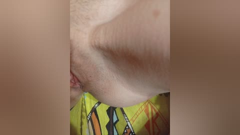 A close-up video showing a light-skinned person's genital area, with visible pubic hair and a colorful patterned fabric beneath.