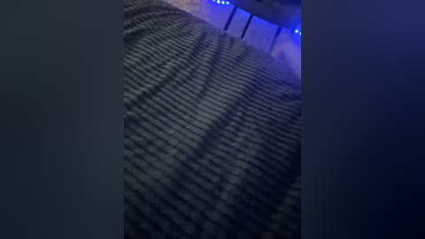 Video of a dimly lit movie theater with a wavy, patterned carpet in shades of gray and blue. Blue ambient lighting casts shadows on the walls and ceiling, creating a moody atmosphere.